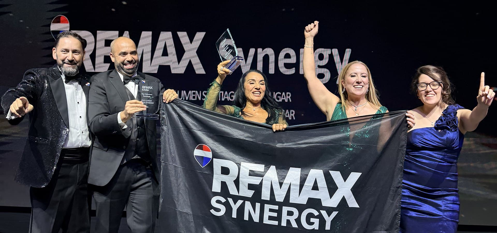 El equipo de RE/MAX Synergy con su bandera en una premiación de RE/MAX Chile